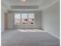 Bright bedroom with large window, tray ceiling, and neutral carpet at 1976 Deco Dr, Kennesaw, GA 30144