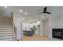 Open-concept living area with hardwood floors, fireplace, stairs, and a view of the modern kitchen and island at 1988 Deco Dr, Kennesaw, GA 30144