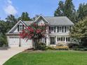 Traditional two-story home with a well-manicured lawn, attached two-car garage and blooming red crape myrtle at 1012 Jubilee Way, Powder Springs, GA 30127