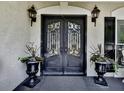 Elegant front door with decorative ironwork, flanked by planters and classic lantern sconces at 1012 Jubilee Way, Powder Springs, GA 30127