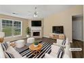 Bright living room with fireplace, ceiling fan, and lots of natural light from large windows at 424 Eglington Trl, Locust Grove, GA 30248