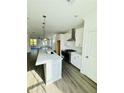 Modern kitchen features a large island, stainless steel appliances, white cabinets, and wood-style flooring at 4440 Sims Park Overlook, Suwanee, GA 30024