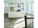Bright kitchen with stainless steel appliances, large island, white cabinets, and light hardwood flooring at 4440 Sims Park Overlook, Suwanee, GA 30024