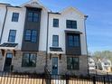Modern townhome showcasing brick and white siding, complemented by black trim and large windows for natural light at 621 Silva St # 124, Cumming, GA 30040