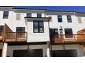 Rear exterior view of modern townhomes featuring white siding, black trim, garages, and wooden balconies at 621 Silva St # 124, Cumming, GA 30040