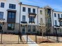 Charming townhome exterior featuring white brick, dark trim, and a well-manicured lawn and black metal fence at 629 Silva St # 128, Cumming, GA 30040