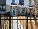 Modern townhome featuring white brick, gray trim, a blue front door, and a black metal fence at 629 Silva St # 128, Cumming, GA 30040