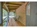 Relaxing porch with a swing, wood flooring, and rustic log cabin details, perfect for enjoying the outdoors at 3208 Paddock Rd, Covington, GA 30014