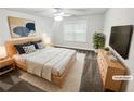 This staged main bedroom has neutral decor, a ceiling fan, and a large window that provides lots of natural light at 3650 Lindsy Brooke Ct, Douglasville, GA 30135