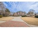 Brick home with circular driveway and manicured lawn at 3133 Saint Ives Country Club Pkwy, Johns Creek, GA 30097