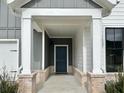 Covered entryway featuring brick columns and a stylish, dark-colored front door at 248 Persimmon Dr, Holly Springs, GA 30115