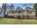 Charming home showcasing an inviting, spacious porch, complemented by red shutters on the windows at 2601 Round Ridge Rd, Loganville, GA 30052