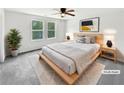 Staged main bedroom featuring contemporary decor, a ceiling fan, and natural light from large windows at 55 Cherohala Ct, Covington, GA 30016