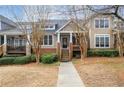 Inviting townhome exterior with a front porch, set amongst mature trees at 905 Freedom Ln, Roswell, GA 30075
