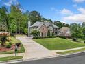 Expansive two-story brick home with lush green lawn and long driveway, set amidst mature trees in a desirable location at 719 Settlers Xing, Canton, GA 30114