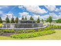 Champions Run community entrance sign with stone accents, landscaping, and water feature under a blue sky at 8588 Preakness Pass, Lithonia, GA 30058