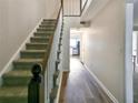 Hallway with carpeted stairs, wooden banister, and hardwood flooring leading to a bright kitchen at 6520 Roswell Rd # 59, Atlanta, GA 30328