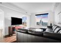 Bright living room with city views, featuring hardwood floors, a large sectional sofa, and a modern entertainment center at 3445 Stratford Ne Rd # 3601, Atlanta, GA 30326