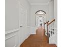 Inviting hallway with hardwood floors, elegant archways, and classic wainscoting leading to staircase at 6329 Edgewater Cv, Fairburn, GA 30213