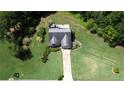 Aerial view of a well-maintained home with a large yard, landscaping, and a long driveway surrounded by lush greenery at 7030 Valley Landing Ct, Cumming, GA 30041