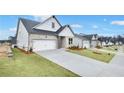 Street view of new homes featuring a two-car garage, well-manicured lawns, and grey brick exteriors at 229 Mooney Rd, Woodstock, GA 30188