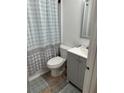 Compact bathroom with a blue and gray patterned shower curtain, gray vanity, and tiled floor at 226 Stayman Dr, Riverdale, GA 30274