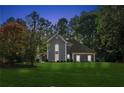 Charming gray two-story home with a manicured lawn and mature trees offering curb appeal at dusk at 1210 Swan Mill Ct, Suwanee, GA 30024