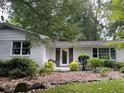 Charming single-story home featuring a white painted brick exterior, well maintained front yard with mature trees at 246 Plantation Sw Rd, Smyrna, GA 30082