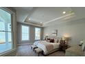 Serene bedroom boasting tray ceilings, a king bed, bench, and bright, natural light at 3587 Fishpond Cir, Dacula, GA 30019