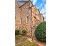 A view of a stone and brick home with a well-maintained lawn and mature shrubbery at 4853 Stonehall Pl, Atlanta, GA 30339