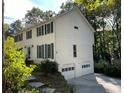View of the home's side featuring a two-car garage and mature landscaping for privacy at 26 Flint Ridge Se Dr, Mableton, GA 30126
