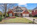 Charming brick home featuring a well-manicured lawn and a two-car garage, all under a beautiful blue sky at 8150 Albritton Downs, Cumming, GA 30041