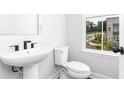 Well-lit powder room featuring a pedestal sink, toilet, and a window with natural lighting at 373 Skylar Se Way, Atlanta, GA 30315