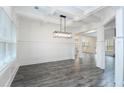 Dining room featuring gray wood floors, white trim and wainscotting, a modern chandelier, and large windows at 1176 Red Oak Blvd, Loganville, GA 30052