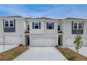 View of townhomes featuring white brick, gray shutters, garages, and detailed landscaping at 212 Sanctuary Drive, Mcdonough, GA 30253