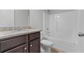 Bathroom with granite countertop, dark brown vanity, and white bathtub at 5400 Deer Run Dr, Conyers, GA 30094