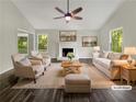 Staged living room featuring a fireplace, hardwood floors, and lots of natural light at 5394 Muirwood Pl, Powder Springs, GA 30127