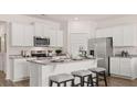 Stylish kitchen with white cabinets, granite countertops, stainless steel appliances and island with seating at 130 Oakchase Park Ln, Hampton, GA 30228
