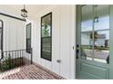 Inviting porch view with a green front door, brick flooring, and modern lighting at 509 Pearl St, Cumming, GA 30040