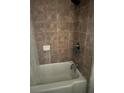 A bright bathroom showcasing the tub and shower tiled in neutral browns at 3230 Vanderbilt Nw Ln, Atlanta, GA 30318