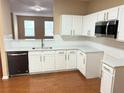 Modern kitchen with white cabinets, quartz countertops, and hardwood floors at 650 Providence Sw Pl, Atlanta, GA 30331