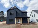 Modern two-story home with dark siding, wood accents, and a covered porch, providing a stylish and inviting entrance at 42 Puckett Se Rd, Emerson, GA 30137