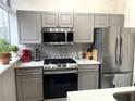 Kitchen with gray cabinetry, stainless steel appliances, and a herringbone backsplash at 2479 Peachtree Ne Rd # 105, Atlanta, GA 30305