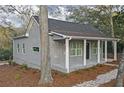 Side view of a gray cottage-style home with a welcoming front porch, gray roof, and manicured landscaping at 1815 River Ne St, Conyers, GA 30012