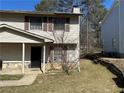 View of the side yard and porch of this two-story home with neutral siding and dark shutters at 1185 Oak Villas Nw Ct, Conyers, GA 30012