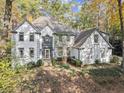 Two-story white brick house nestled in a wooded setting at 2680 Spalding Dr, Sandy Springs, GA 30350