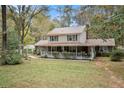 Charming two-story home with a long front porch surrounded by mature trees and a green lawn at 112 Christopher Ln, Stockbridge, GA 30281