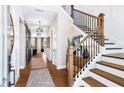 Inviting hallway with hardwood floors, decorative lighting, staircase, and large mirror, leading to an open living space at 729 Keystone Dr, Woodstock, GA 30188