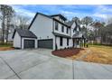 Side exterior view of gray home with a three-car garage and long driveway on a spacious lot at 3745 Pilgrim Mill Rd, Cumming, GA 30041
