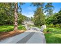 Serene view of the property entrance with stone pillars and an elegant driveway leading to a beautiful home surrounded by trees at 3488 Tuxedo Nw Rd, Atlanta, GA 30305